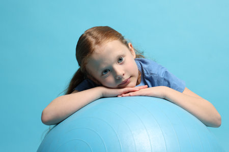 Person resting on fitness ball against light blue backgroundの写真素材