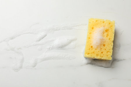 Yellow sponge with foam on white background, top view. Space for textの写真素材