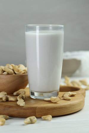 Fresh cashew milk in glass and nuts on white wooden table, closeupの写真素材
