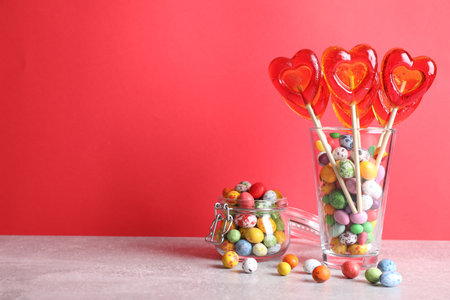 Delicious heart shaped lollipops and dragees on table. Space for text