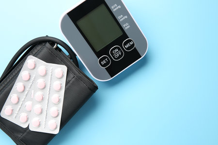 Blood pressure measuring device and pills on light blue background, top viewの写真素材