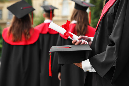 Student with graduation hat and diploma at ceremony outdoors, selective focusの写真素材