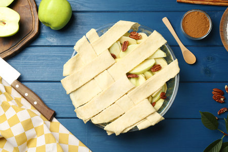 Flat lay composition with raw homemade apple pie and ingredients on blue wooden tableの写真素材