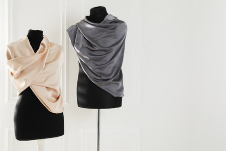 Mannequins wrapped in fabric near light wall. Space for textの写真素材