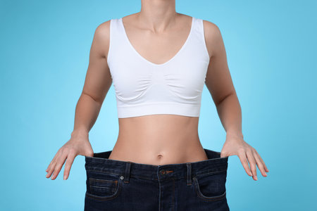 Person wearing oversized jeans against light blue background, closeupの写真素材