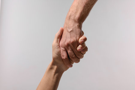 Help and support. People holding hands on light gray background, closeup