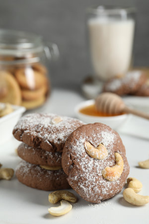 Tasty chocolate cookies with cashew and powdered sugar on white table, closeupの写真素材