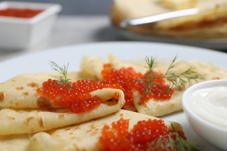 Tasty crepes with red caviar, dill and sauce on gray table, closeupの写真素材