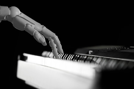 Artificial intelligence. Robot hand playing synthesizer on black background, closeupの写真素材