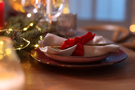Beautiful dishware and Christmas lights on wooden table indoors, closeupの写真素材