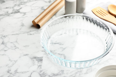 Glass casserole and other cooking utensils on white marble table, closeupの写真素材