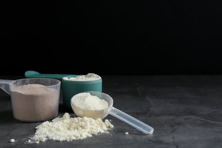 Protein powders in scoops on gray textured table, space for textの写真素材