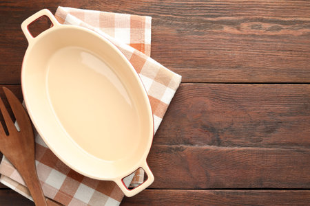 Ceramic casserole and slotted turner on wooden table, top view. Space for textの写真素材