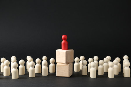 Competition concept. Human figure on wooden cubes and other ones behind against black backgroundの写真素材
