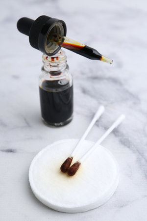 Bottle of aqueous iodine with pipette and cotton swabs on white marble table, closeupの写真素材