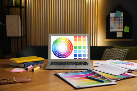 Designer's workplace with laptop, stationery and palettes on wooden table indoorsの写真素材