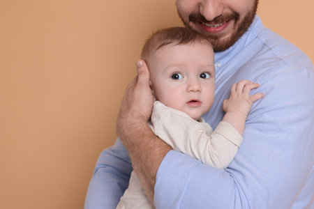 Father with his cute baby on beige background, space for textの写真素材