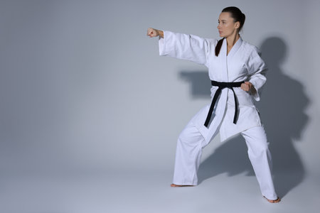 Person in martial arts uniform practicing karate on grey backgroundの写真素材