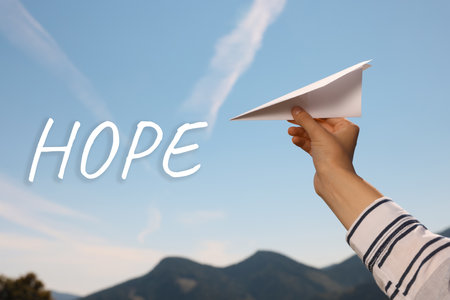 Hope. Hand holding paper plane against blue sky, closeupの写真素材