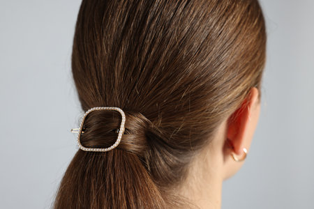 Teenage girl with stylish hair clip on light grey background, back viewの写真素材
