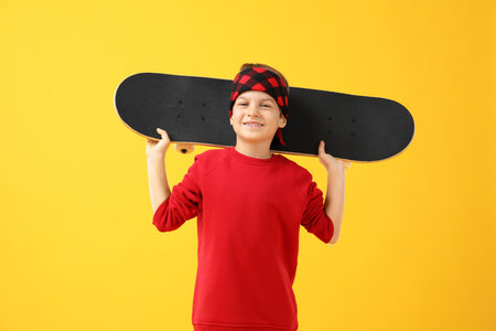 Little boy with skateboard on yellow backgroundの写真素材