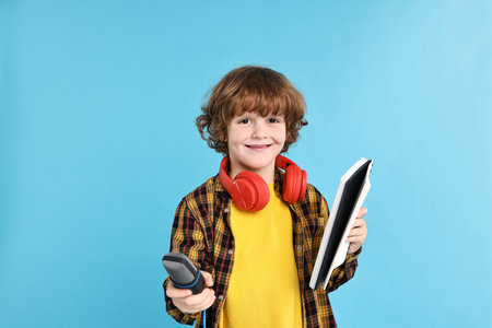 Little boy with microphone, headphones and notebook on light blue backgroundの写真素材