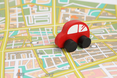 Red toy car on city map. Road trip