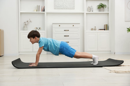 Boy doing exercise on fitness mat at home. Sport activityの写真素材
