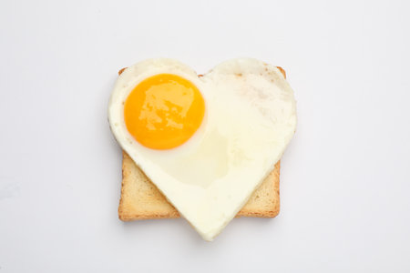 Tasty fried egg in shape of heart with toast isolated on white, top viewの写真素材