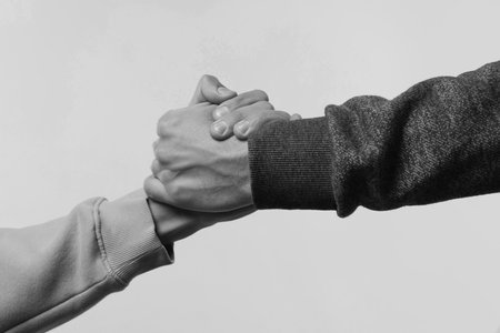 Help and support. People holding hands on light gray background, closeup. Toned in black and whiteの写真素材