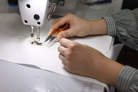 Woman working with sewing machine in professional workshop, closeup