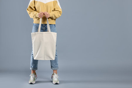Woman with blank shopper bag on gray background, closeup. Mockup for design
