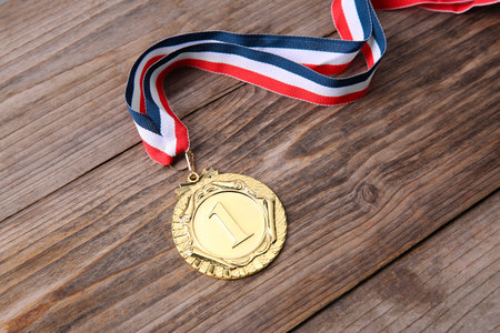 Golden medal with striped ribbon on wooden background, closeupの写真素材