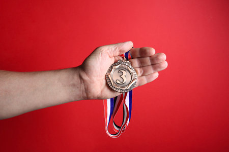 Man with bronze medal on red background, closeupの写真素材