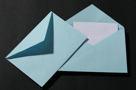 Paper envelopes with letter on black background, top view. Mockup for designの写真素材