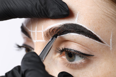 Young woman undergoing henna eyebrows dyeing procedure on light background, closeupの写真素材