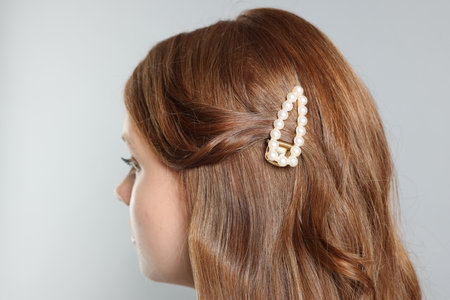 Teenage girl with stylish hair clip on light grey background, closeupの写真素材