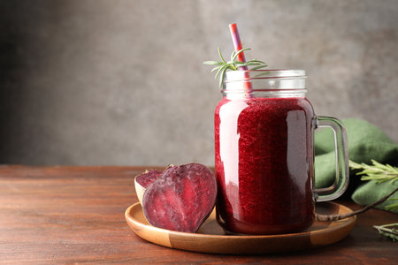 Fresh beetroot smoothie in mason jar and vegetables on wooden table, closeup. Space for textの写真素材