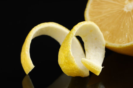 Fresh lemon peel and fruit on black glass surface, closeupの写真素材
