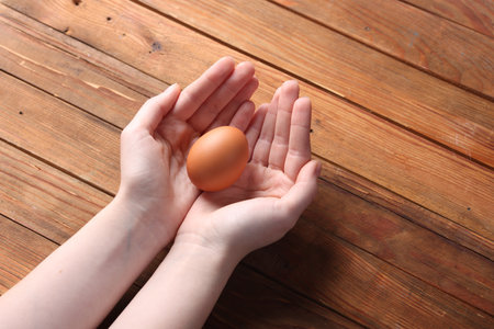 Woman with raw egg at wooden table, closeupの写真素材