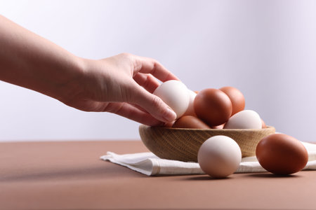 Woman with raw eggs at brown table, closeupの写真素材