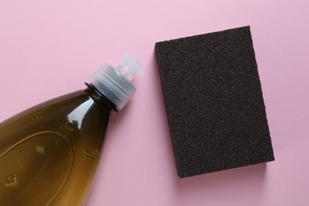 Sponge and bottle with detergent on pink background, flat layの写真素材