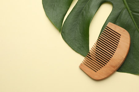 Wooden comb and monstera leaf on beige background, top view. Space for textの写真素材