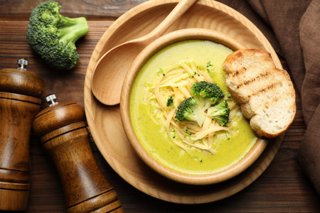 Delicious broccoli cream soup served on wooden table, flat layの写真素材
