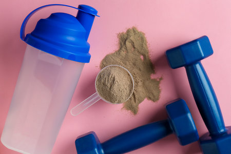 Protein powder, shaker and dumbbells on pink background, flat layの写真素材