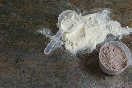 Protein powders and scoops on grey textured table, flat lay.の写真素材
