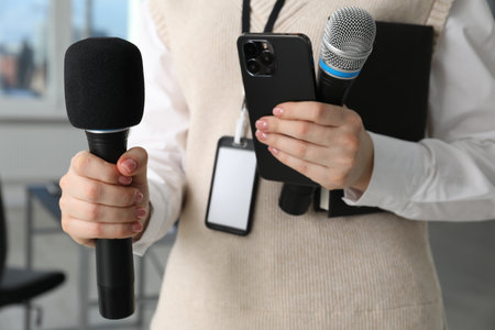 Journalist with microphones, smartphone and notebook indoors, closeupの写真素材