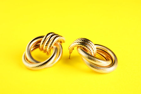 Beautiful bijouterie. Stylish earrings on yellow background, closeup