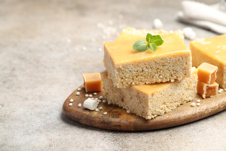 Delicious puffed rice bars, candies and mint on gray textured table, closeup. Space for text