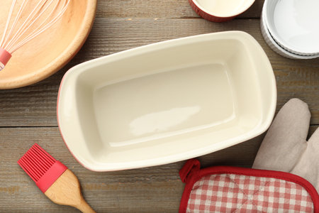 Ceramic casseroles and other cooking utensils on wooden table, flat lay